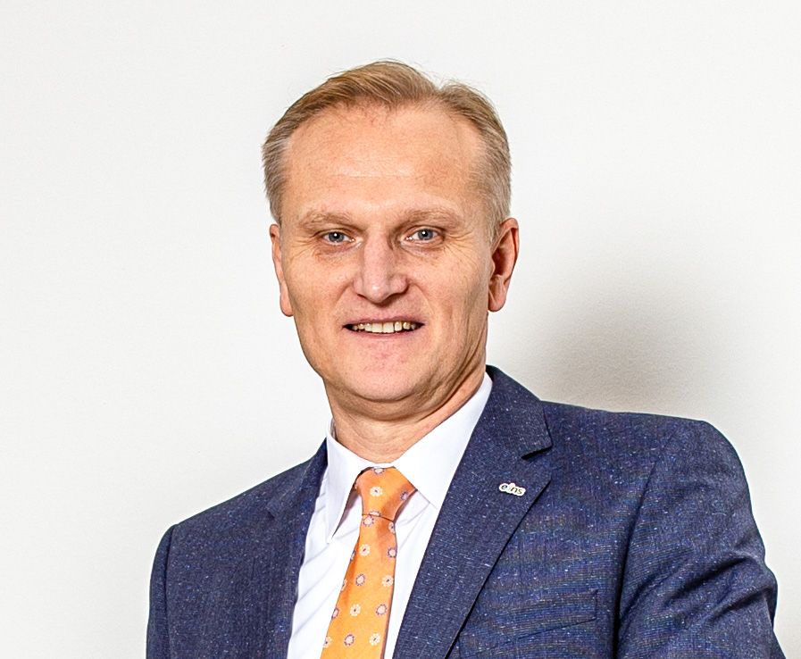 Portrait von Roland Warner in blauem Sakko und gelber Krawatte