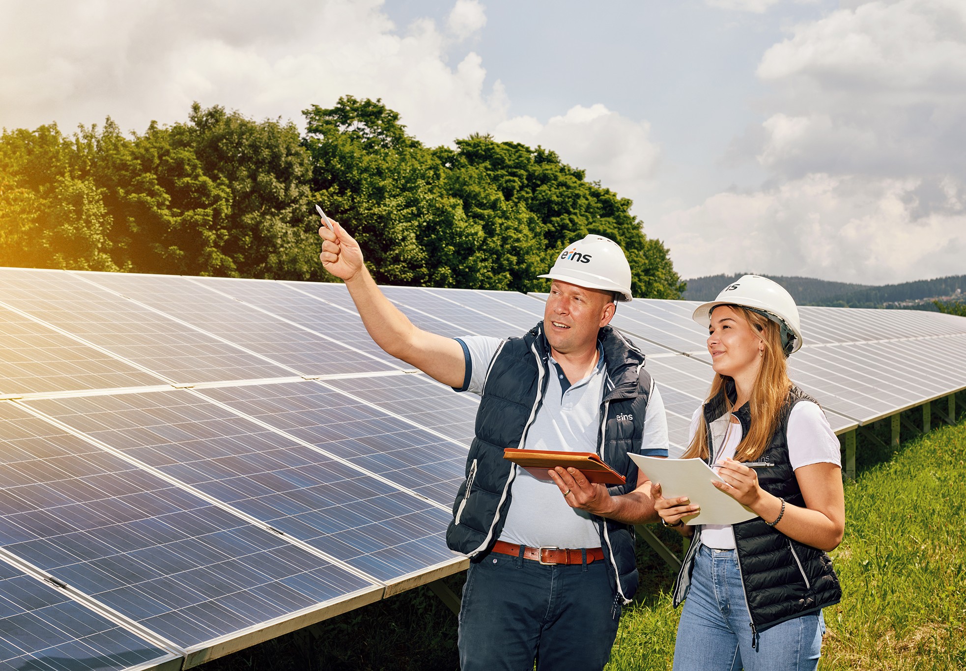 Zwei Personen stehen vor Photovoltaikanlagen und besprechen sich
