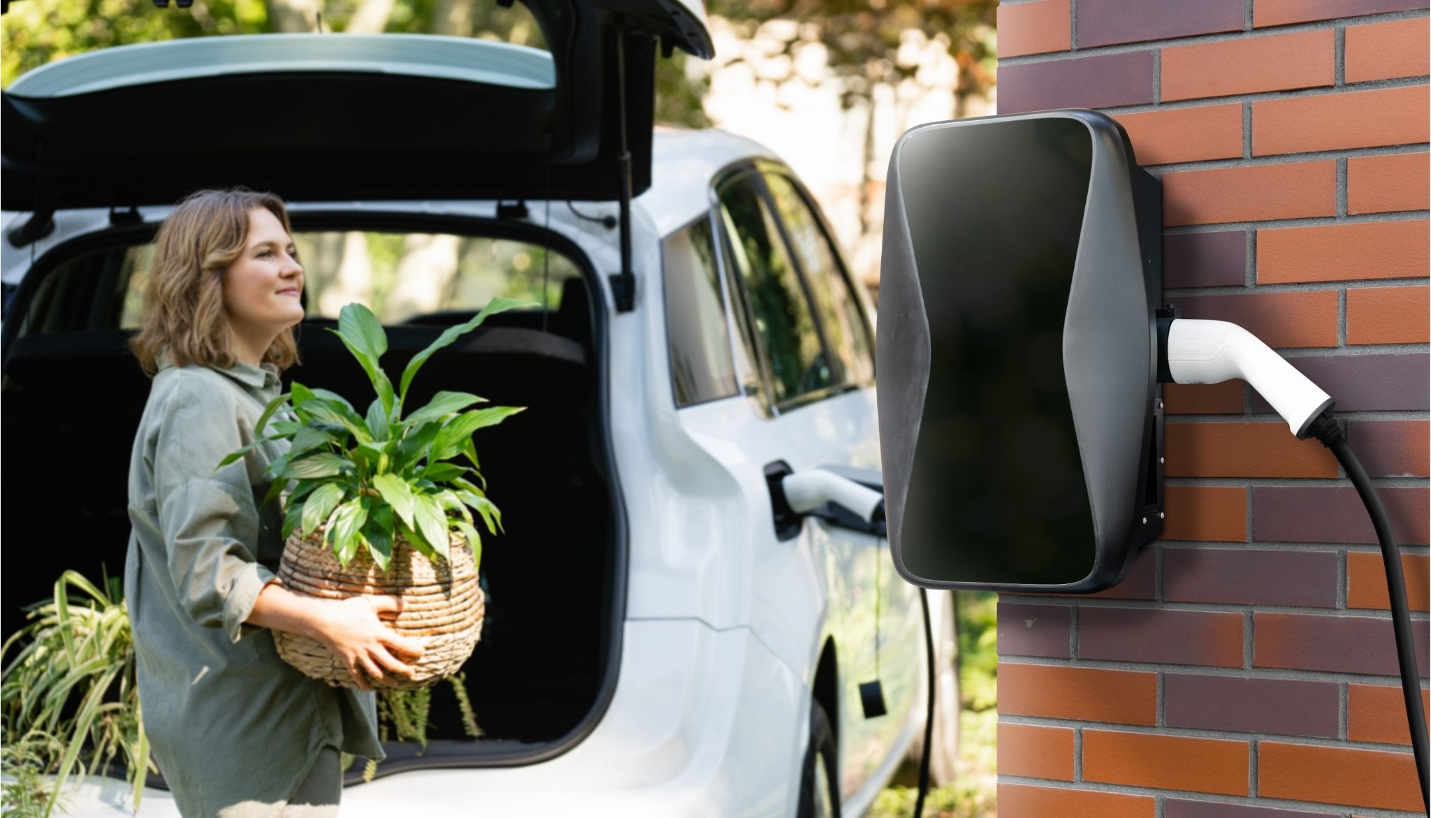 Auto wird über Wallbox geladen, Frau räumt pflanzen aus dem Kofferraum.