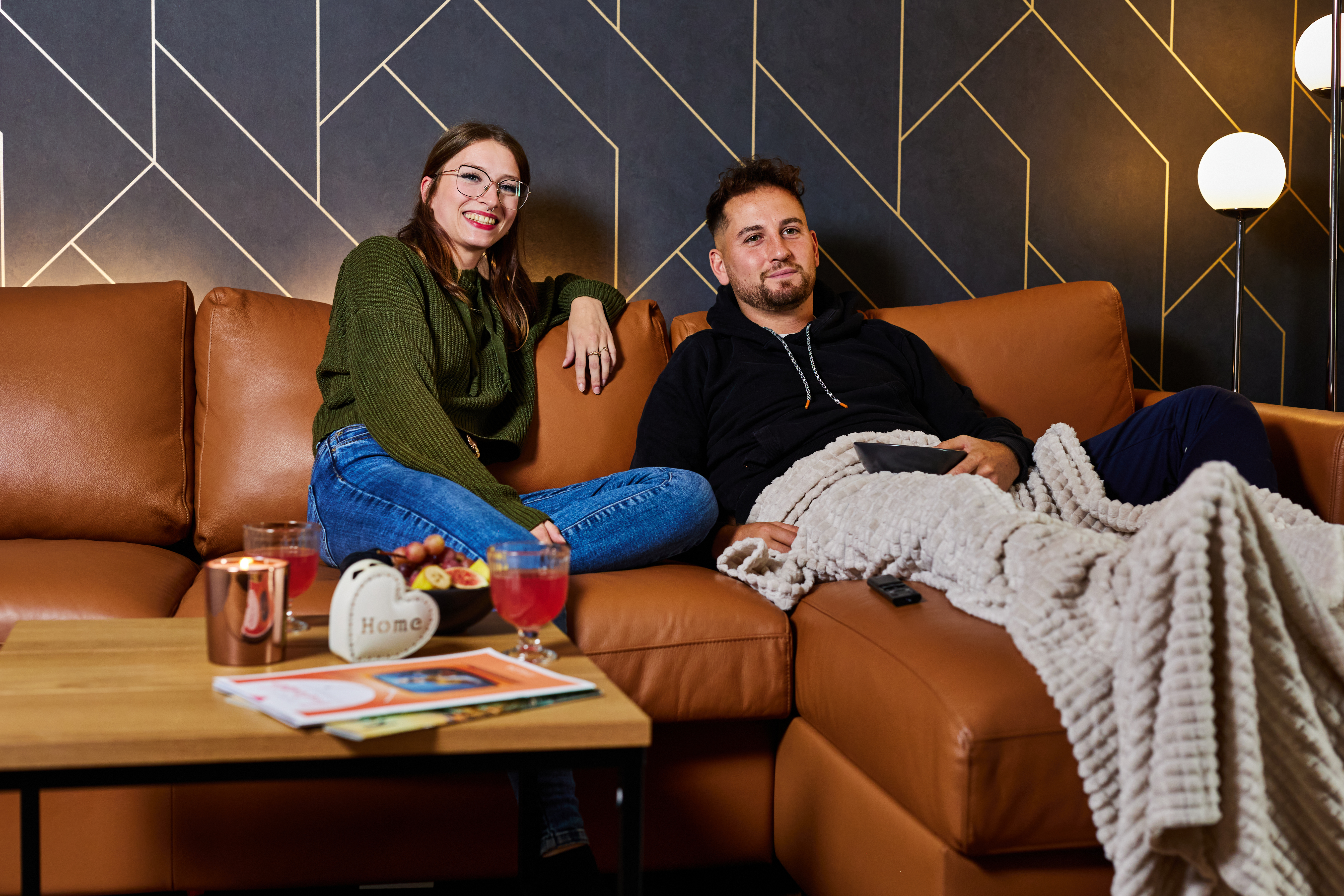 Man und Frau sitzen gemeinsam auf der Couch und schauen TV mit ihrem neuen Glasfaseranschluss