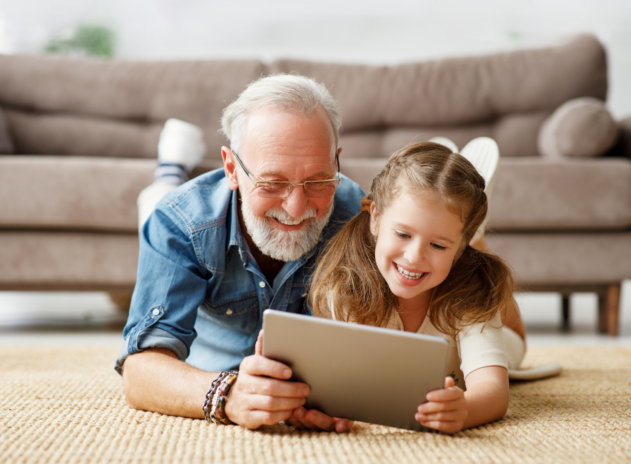Großvater und Enkeltochter schauen auf Tablet