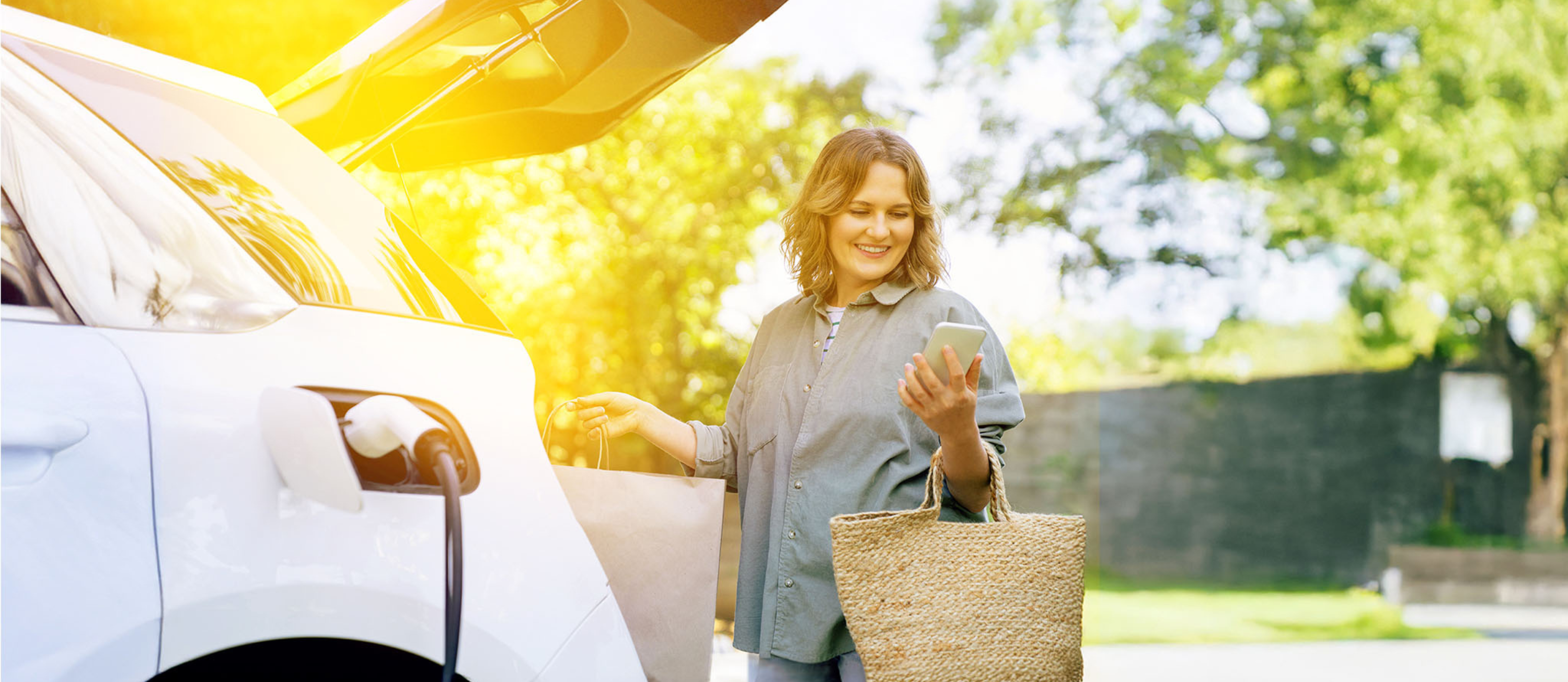 Weißes E-Auto mit Pflanzen im Kofferraum.