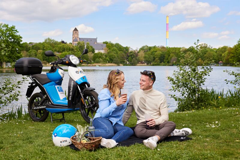 E-Roller und Pärchen vor Schlossteich