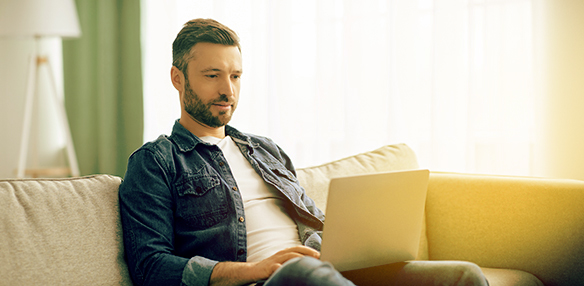 Junger Mann sitzt auf dem Sofa und macht sich schlau.