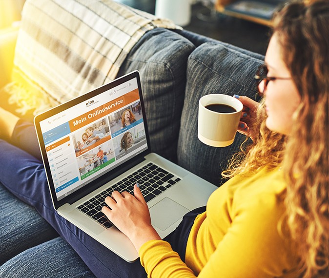 Eine Frau mit Laptop auf der Couch nutzt den eins Onlineservice